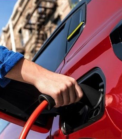 Una persona carga un vehiculo electrico Coche eléctrico en proceso de carga - Stellantis &You